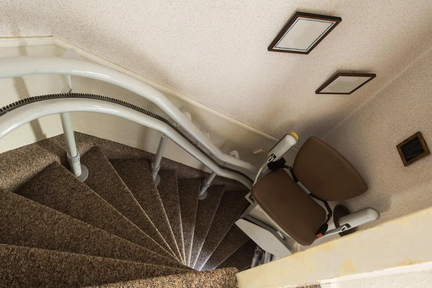 Silla salvaescaleras instalada en una escalera estrecha de caracol dejando paso libre para subir andando