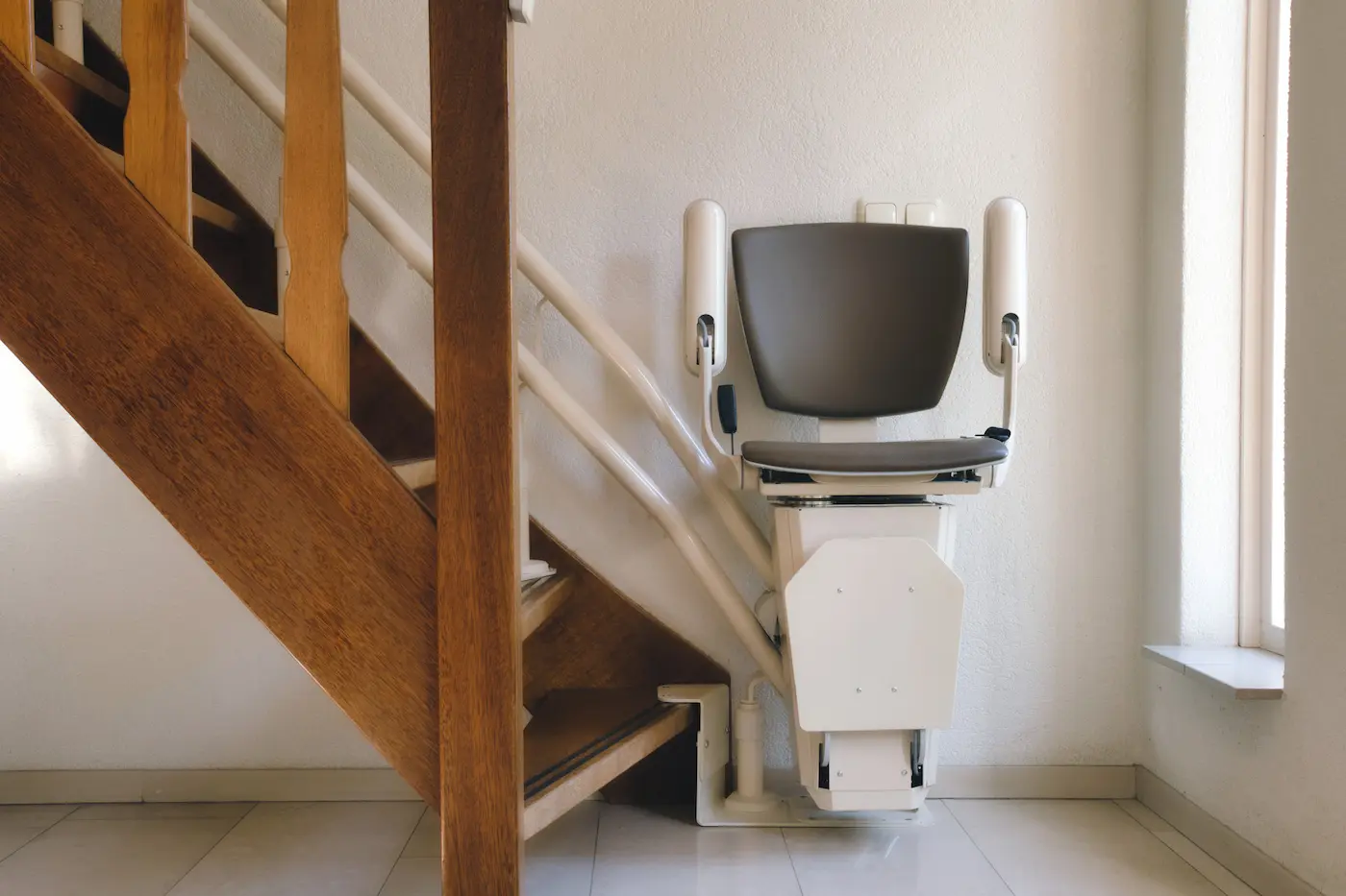 Silla salvaescaleras plegada contra el raíl en una escalera de una vivienda de Pozuelo de Alarcón